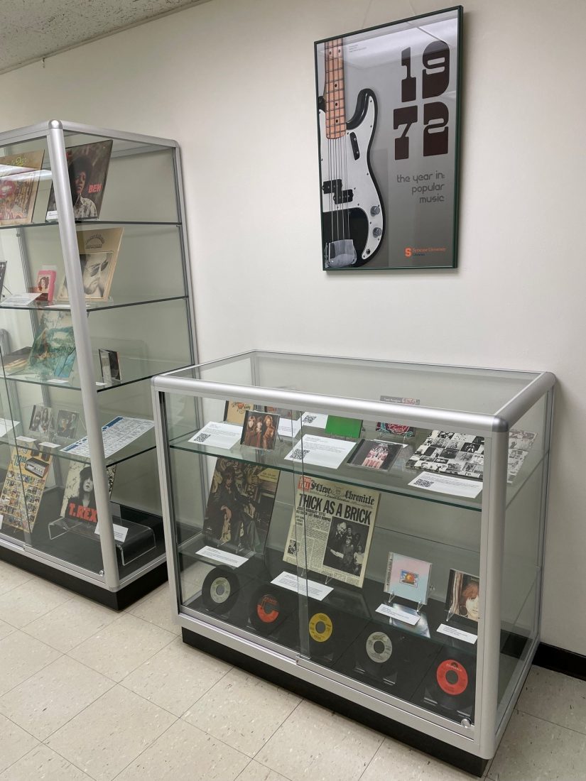 glass display cases with albums, poster on wall with guitar and 1972