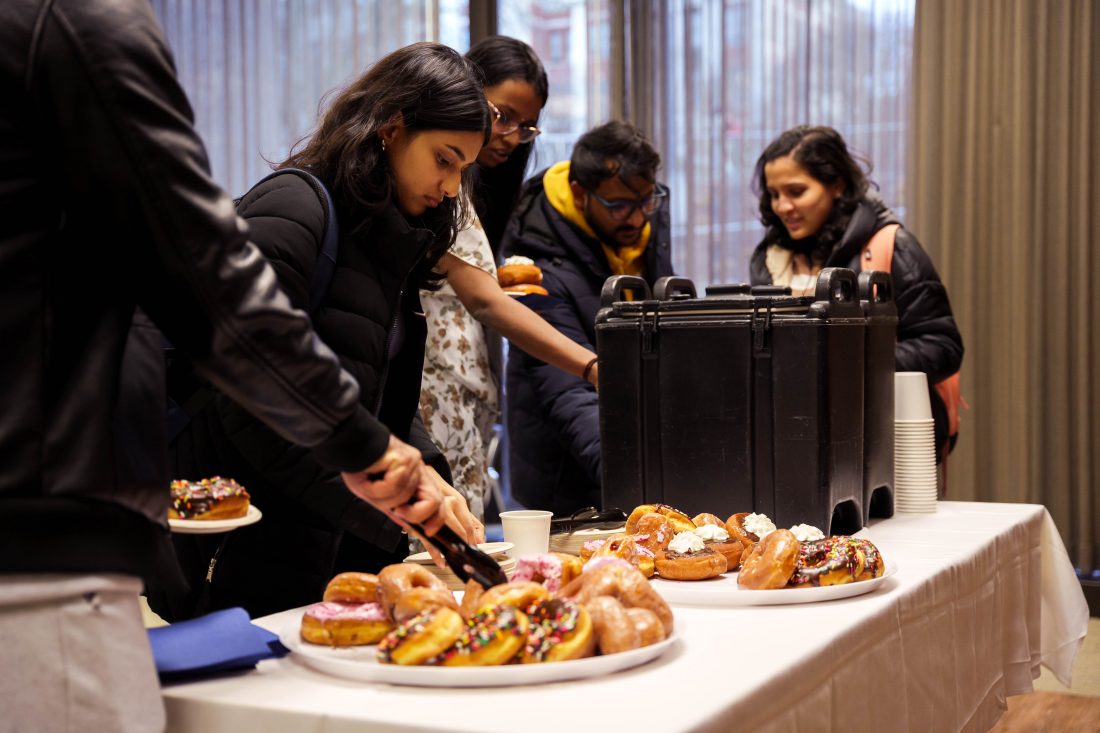 table with donuts and coffee, people helping themselves