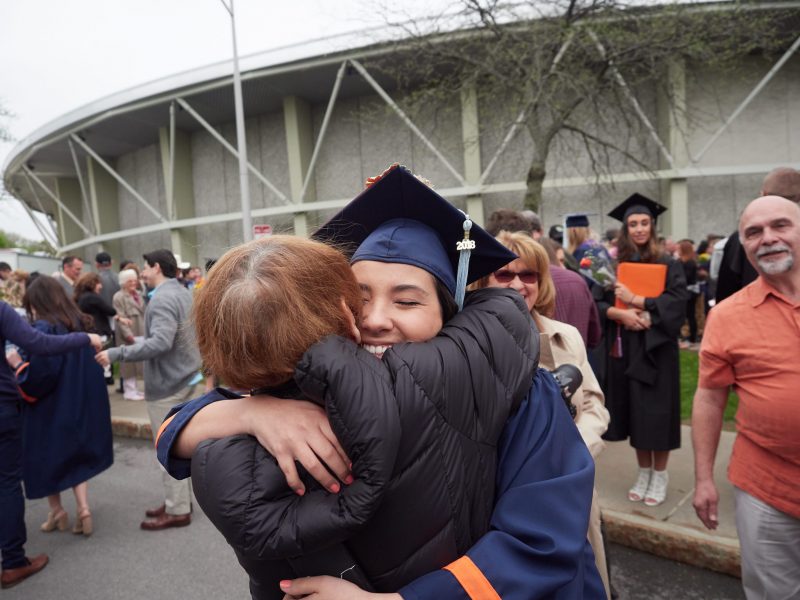 a graduate hugs their mother after a graduation event outside of manley field house