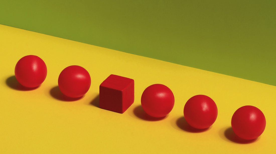 Red spherical building blocks sitting side by side, with one cube block in the mix.