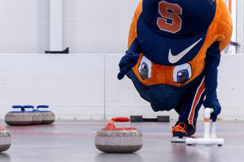 Otto the Orange practices their curling at Tennity Ice Skating Pavilion.