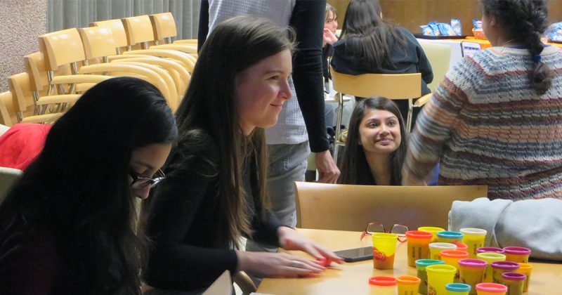 several students smiling, talking, playing with play-dough