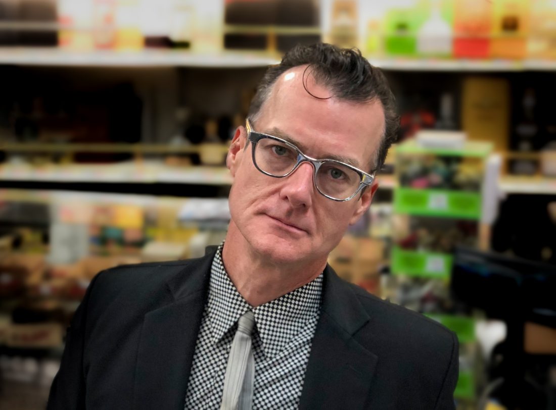 white mail wearing glasses and shirt, tie and jacket in front of colorful background