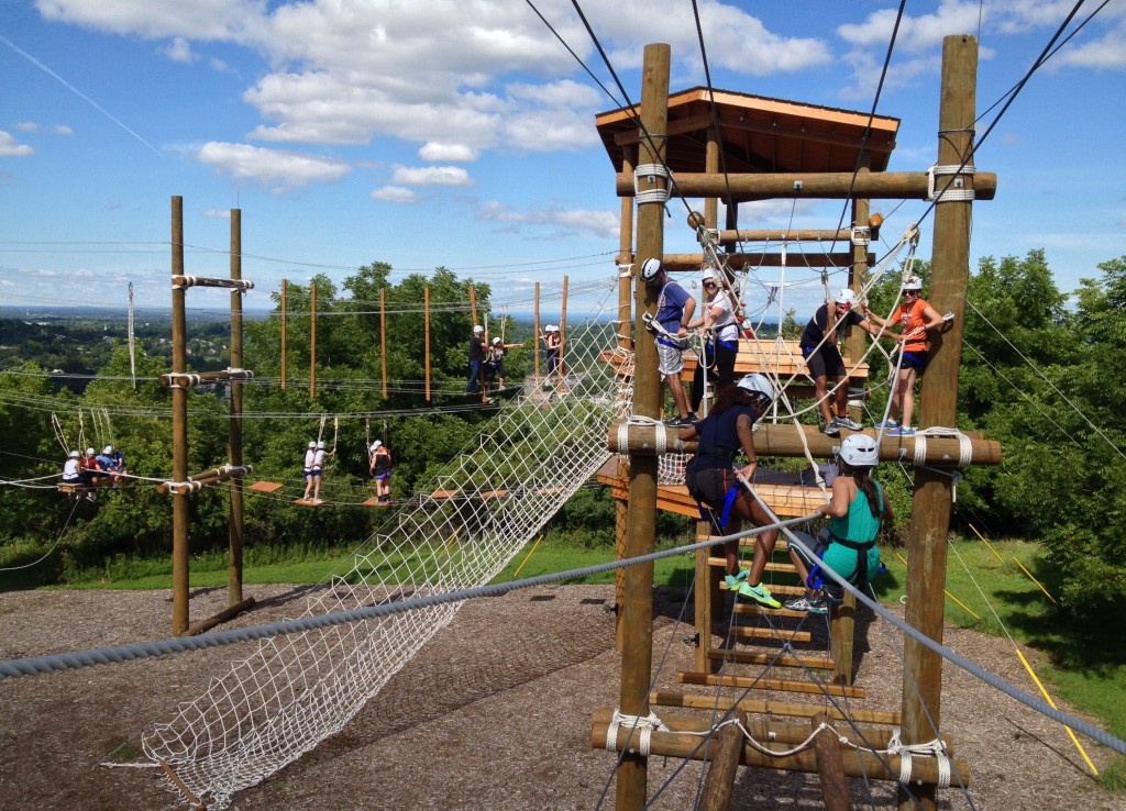 Participants walking on cables and holding rope as they move through the Outdoor Challenge Course.