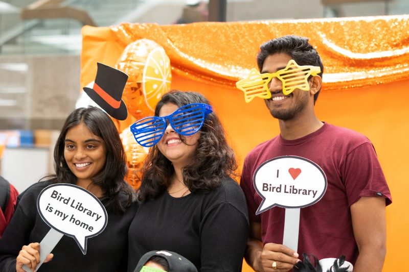 three students with oversized sunglasses and signs that read 