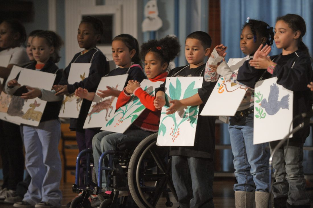 elementary students on a stage wearing posters with art