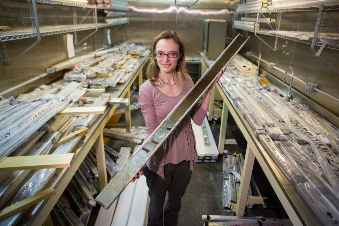 Doctor Thomas holding up a sediment core from the high Arctic in a room of samples.