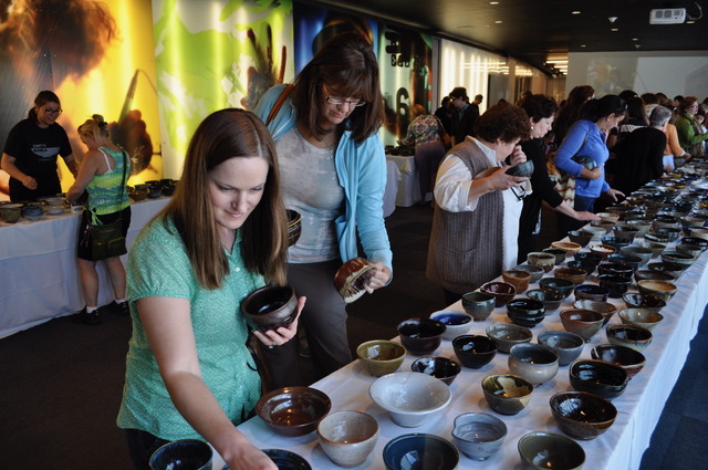 A group of people look at ceramic bowls on a table