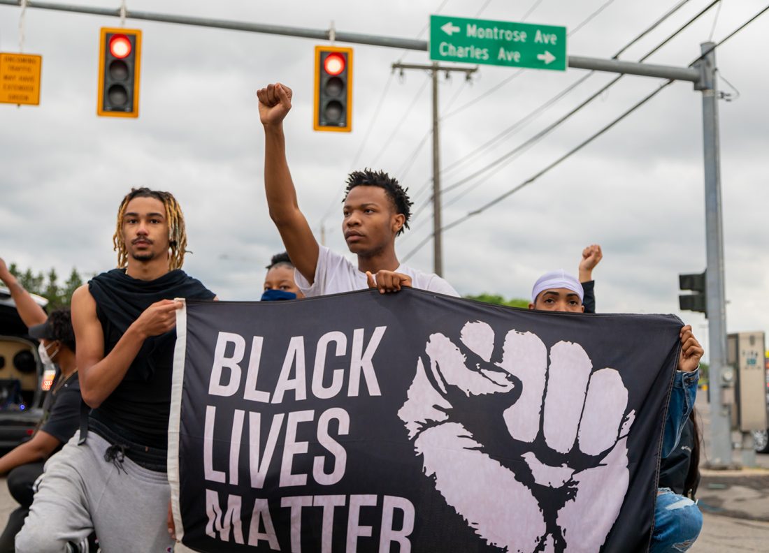 Three young Black men hold Black Lives Matter flag