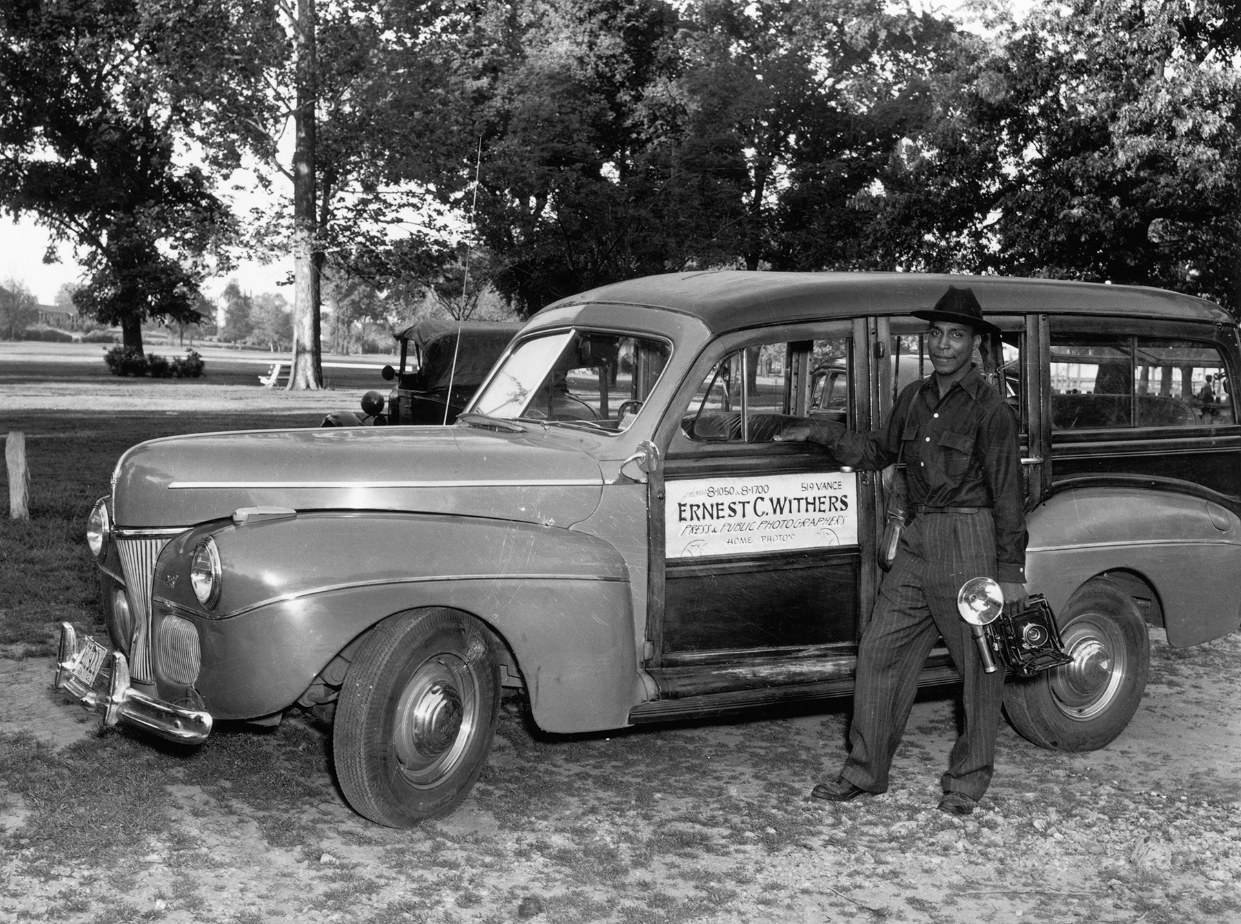 Black and white image of Ernest Withers circa 1940, standing next to a car