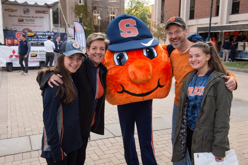 family of four poses around Syracuse University mascot Otto the Orange