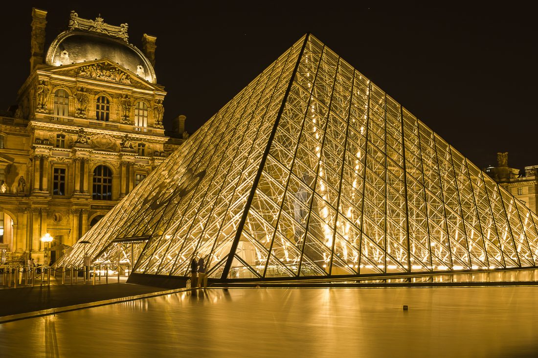 Louvre glass pyramid lit up with warm lights at night
