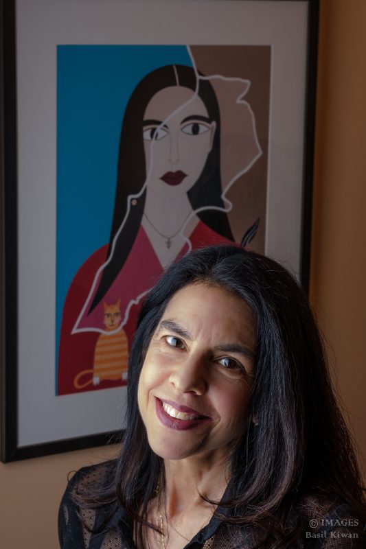 portrait of woman with long hair in front of artwork 