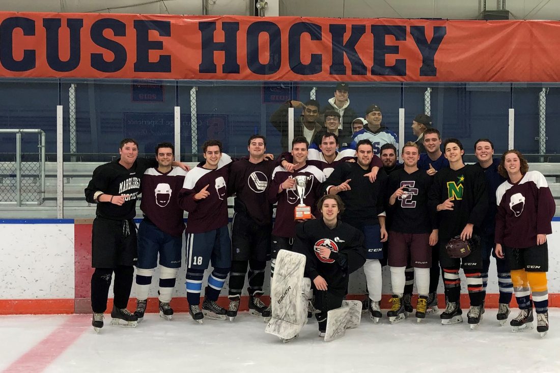 Group photo of a hockey team. The player in the center holds the championship trophy.