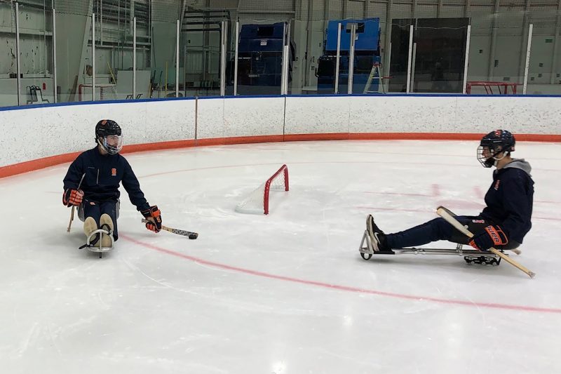 A sled hockey player attempts to move the puck around an opponent.