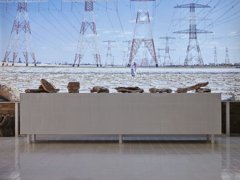 A group of small sculptures in front of a screen showing power lines