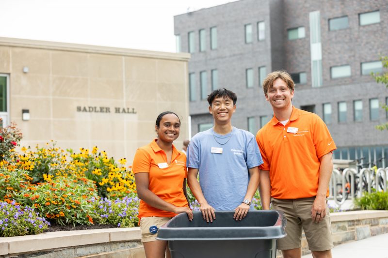 Three Orientation Leaders stand together in front of Sadler Hall