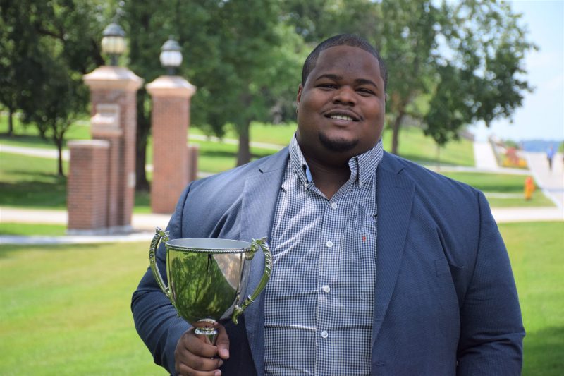 black man holding trophy outside