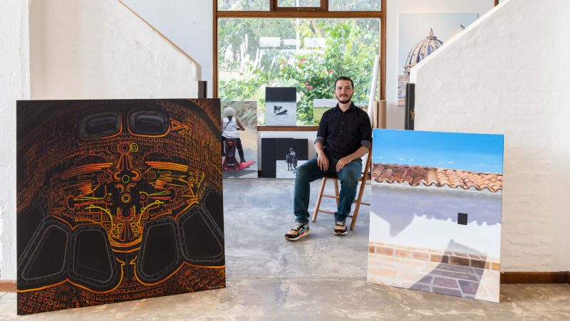 Juan José Cielo sits in a chair, surrounded by his work.