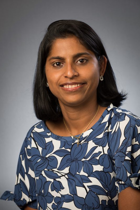 A close-up color photo of Dr. Latha Ramalingam smiling for the camera. 