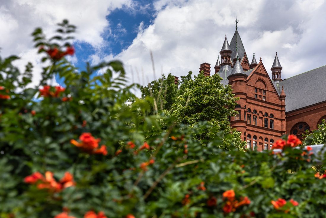 Crouse College rises above green foliage with orange flowers.