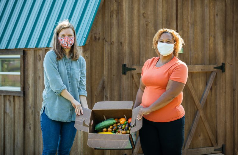 Meg Lowe and Syeisha Byrd holding a box of vegetables from Pete's Giving Garden