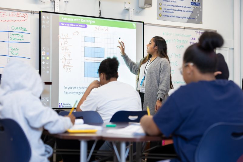 A teacher of color teaching math in front of a class