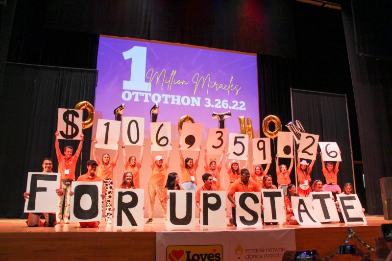 OttoTHON's executive board holds up posterboards that say 