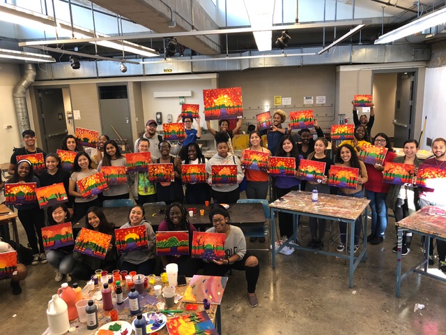 A group of fullCIRCLE participants posing with their art, from a paint night!