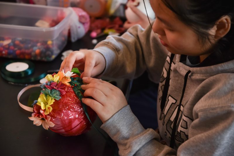 Figure crafting a red ball with felt flowers