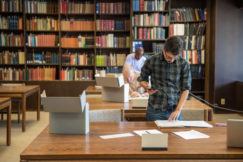 two men standing at table in Special Collections Reading Room going through boxes of materials