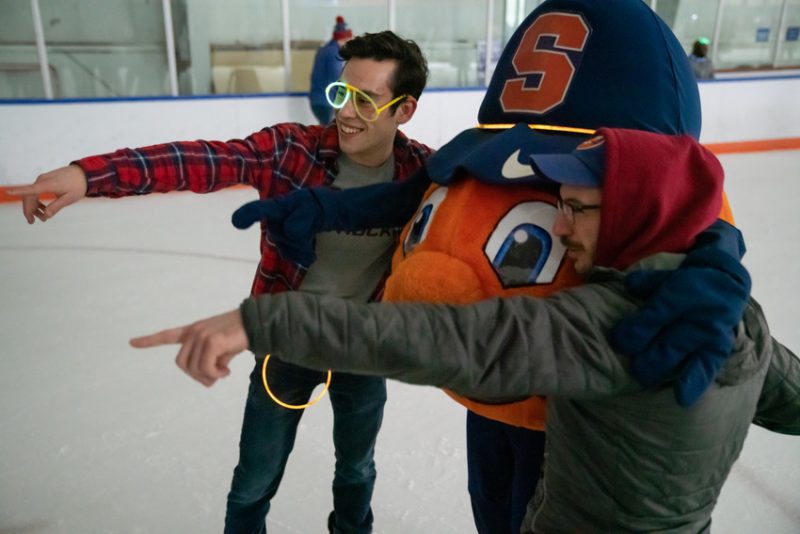 Students point at the camera with Otto the Orange at glow skate