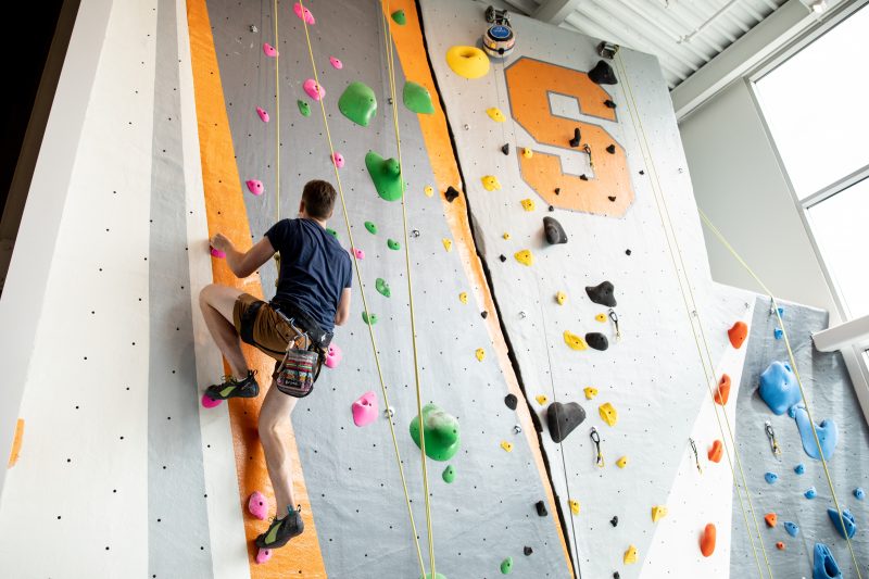 Man climbing rock wall at the Barnes Center at The Arch