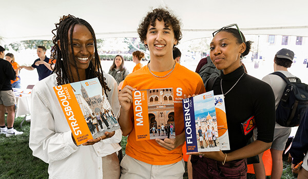 Three students holding books in their hands about study abroad.