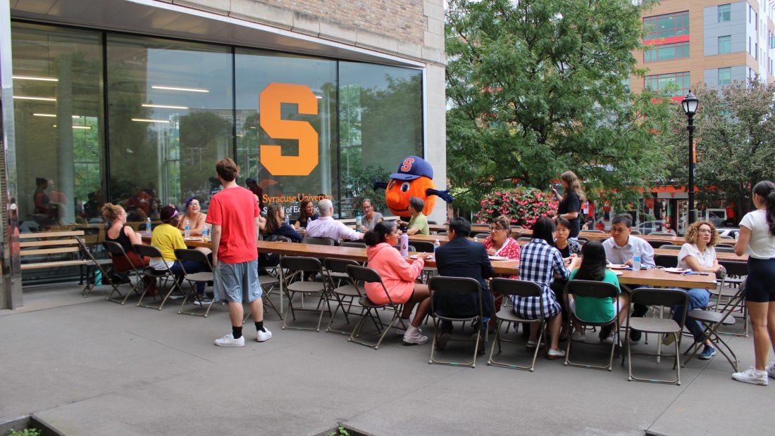 people at tables and standing at the school of education picnic