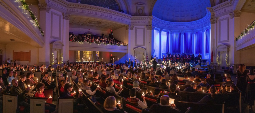 Attendees hold small, lighted candles as they look toward the Hendricks main stage. 