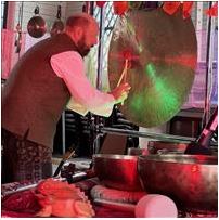 person playing a gong and various instruments in the background