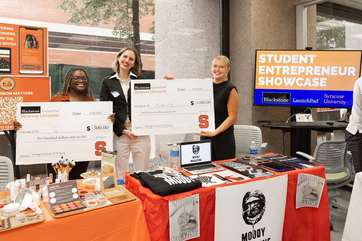 students tabling hold up giant checks