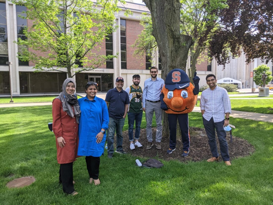 Otto standing with students under a tree between Hendricks Chapel and Physics Building.