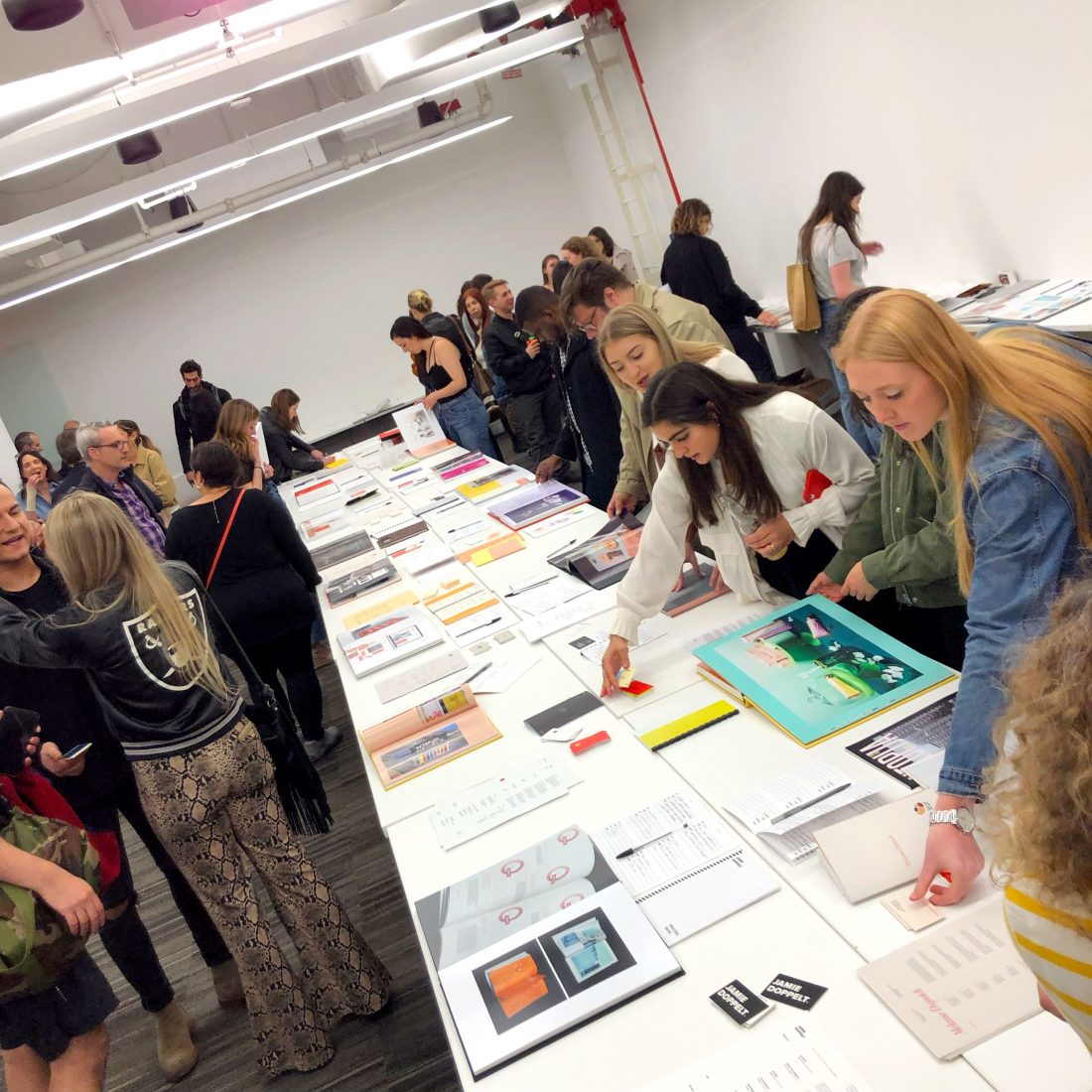A group of people look at portfolios of design work on a table