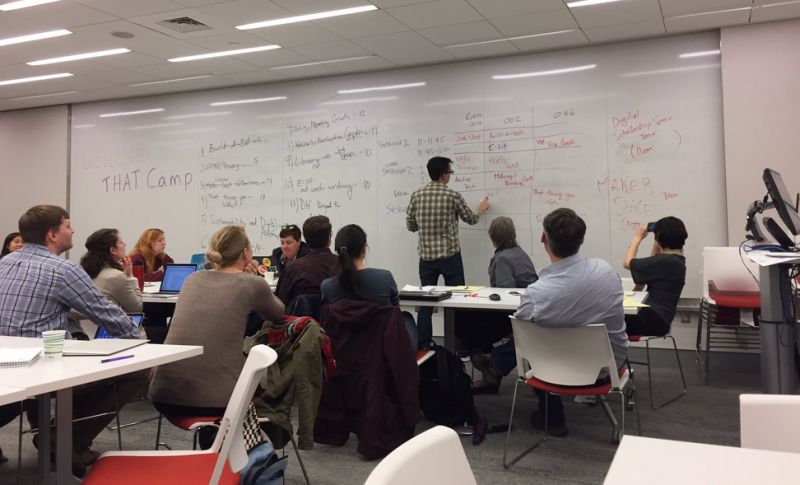 Participants at THATCamp CNY in 2017 in Bird Library. Room full of participants, one person writing on whiteboard.