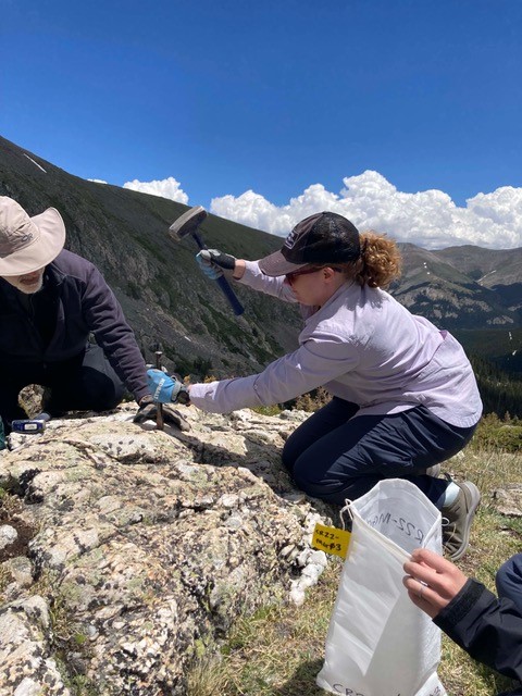 Team collects rock samples on side of mountain.