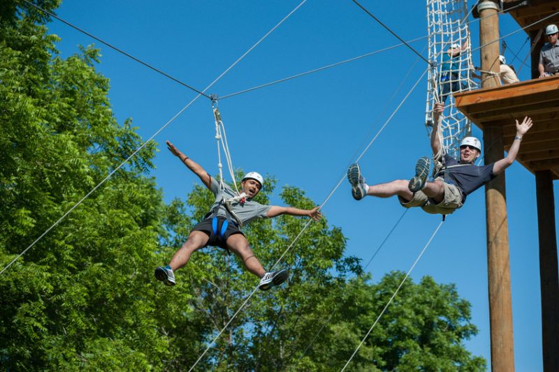 Two people ziplining out of a Challenge Course Tower on the Syracuse University campus.
