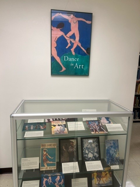 display case with poster above it showing two figures dancing and words Dance in Art