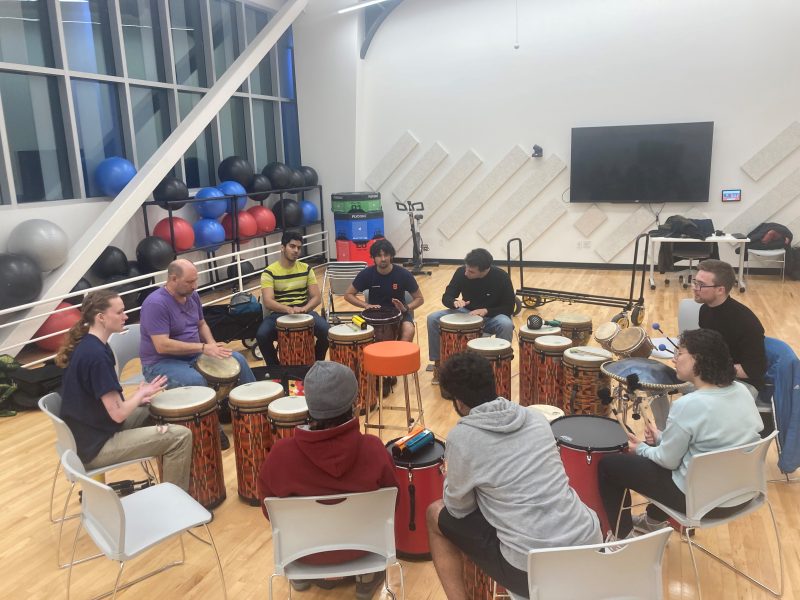 students sitting in a fitness room playing drums together