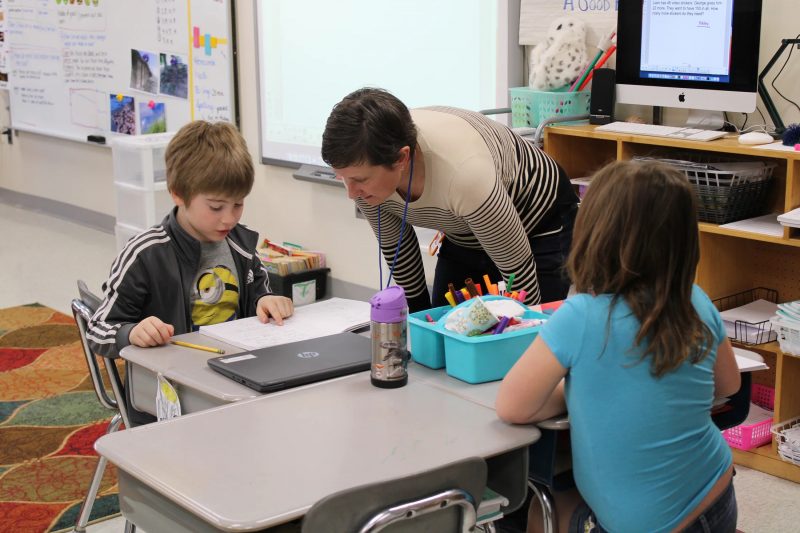 a principal talks to two elementary students in a classroom