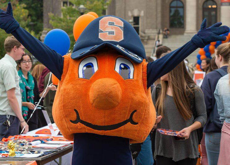 Otto stands with his arms up in front of a table at the Fall Involvement Fair.