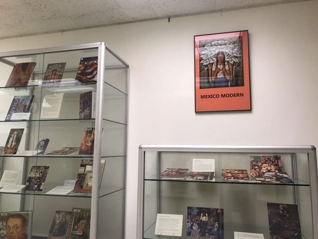 display cases featuring books and art with poster above it that reads Mexico Modern