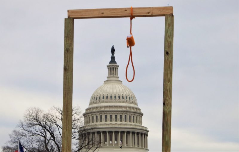 A photograph of the United States Capitol with gallows and a noose in the foreground