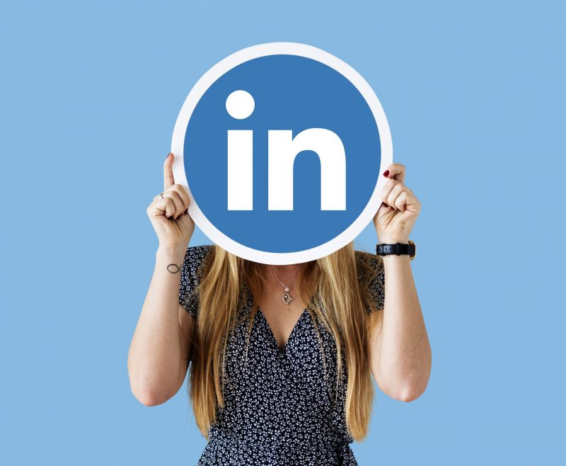 Woman holding circle of LInkedIn logo in front of her face